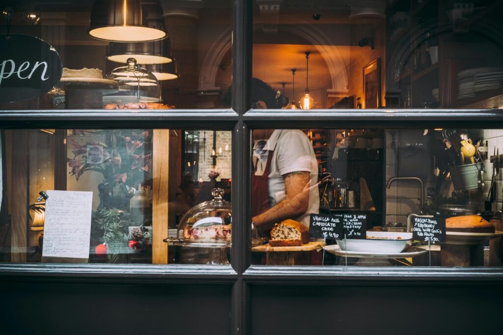 Warm bakery scene in London through window showcasing pastries and chef at work.